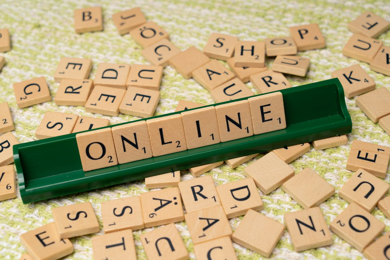 Scrabble tiles spelling online on a green tray amidst scattered tiles, symbolizing digital connectivity and language.